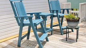 Une terrasse avec deux chaises Adirondack bleues et une petite table.