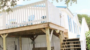 Un bâtiment blanc avec des volets bleus et une terrasse en bois.