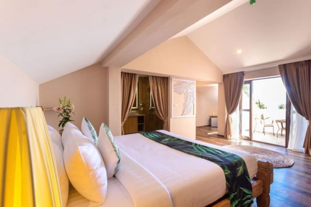 Un dormitorio espacioso con una cama grande, una puerta corrediza de vidrio a un balcón y vistas al exterior.