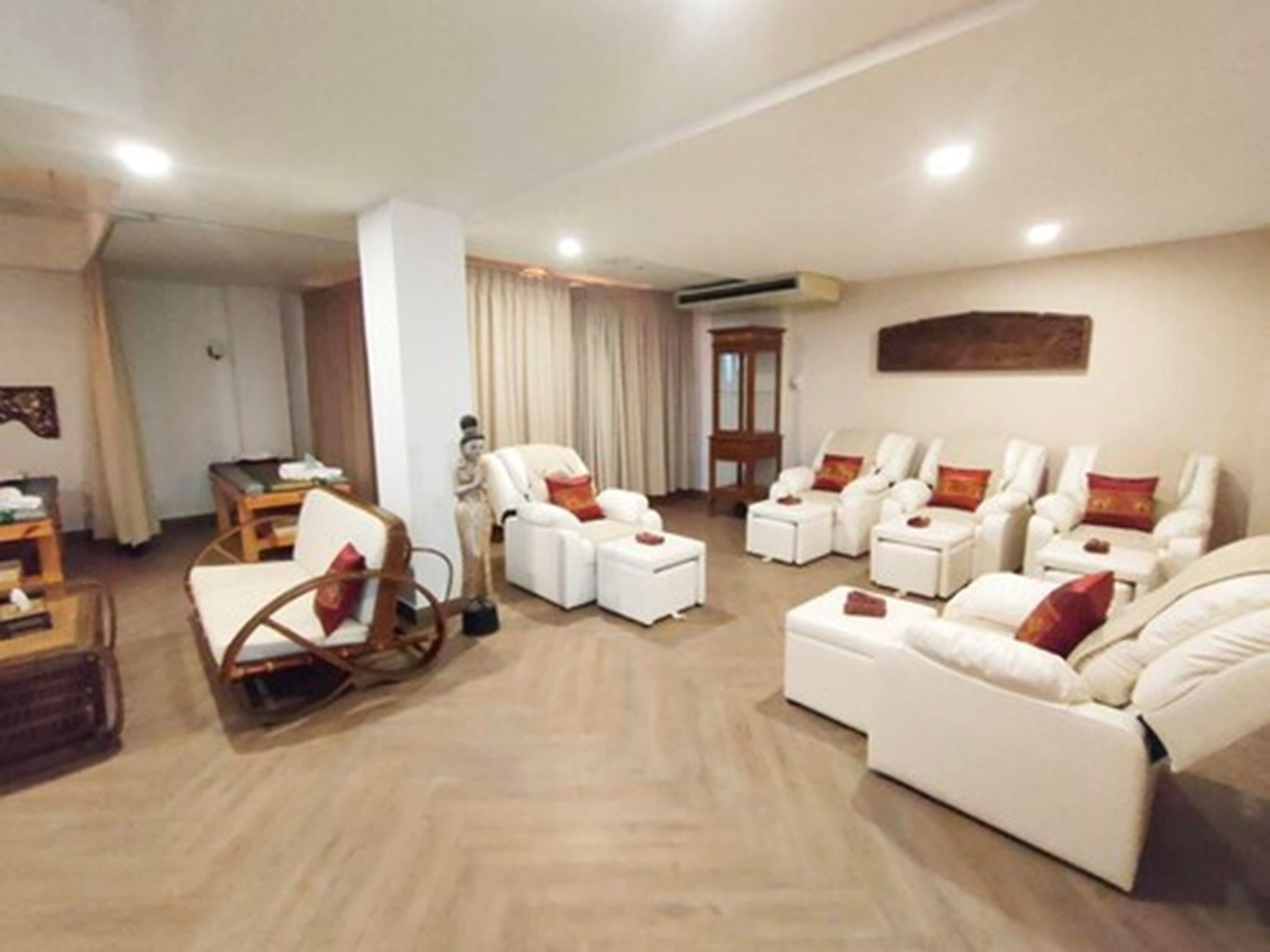Amplia sala de estar con varias opciones de asientos, incluyendo sofás y sillones, una mesa de centro de madera y una estatua decorativa.