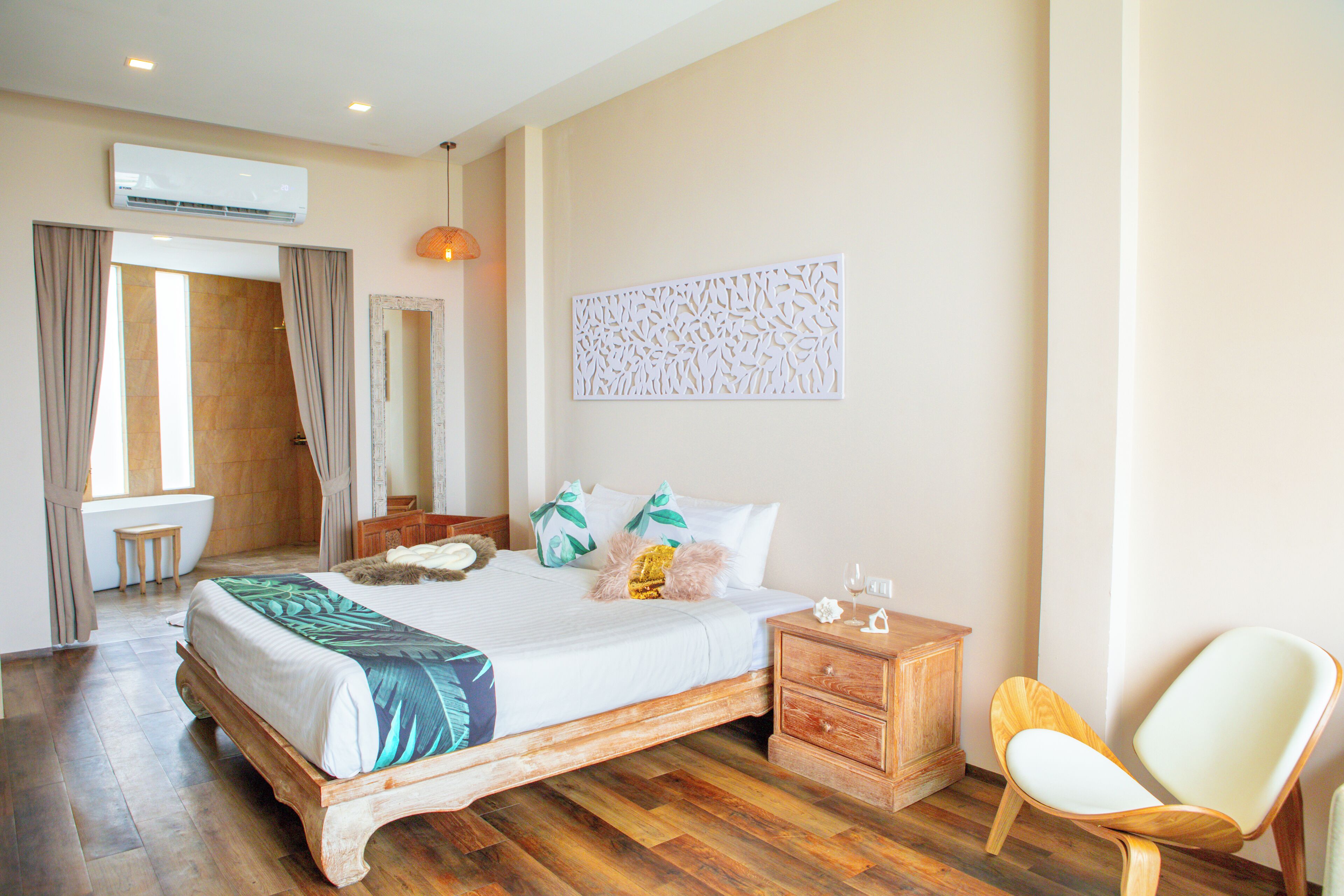A bedroom with a wooden bed, a nightstand, a chair, a wall-mounted air conditioner, and a window with curtains.