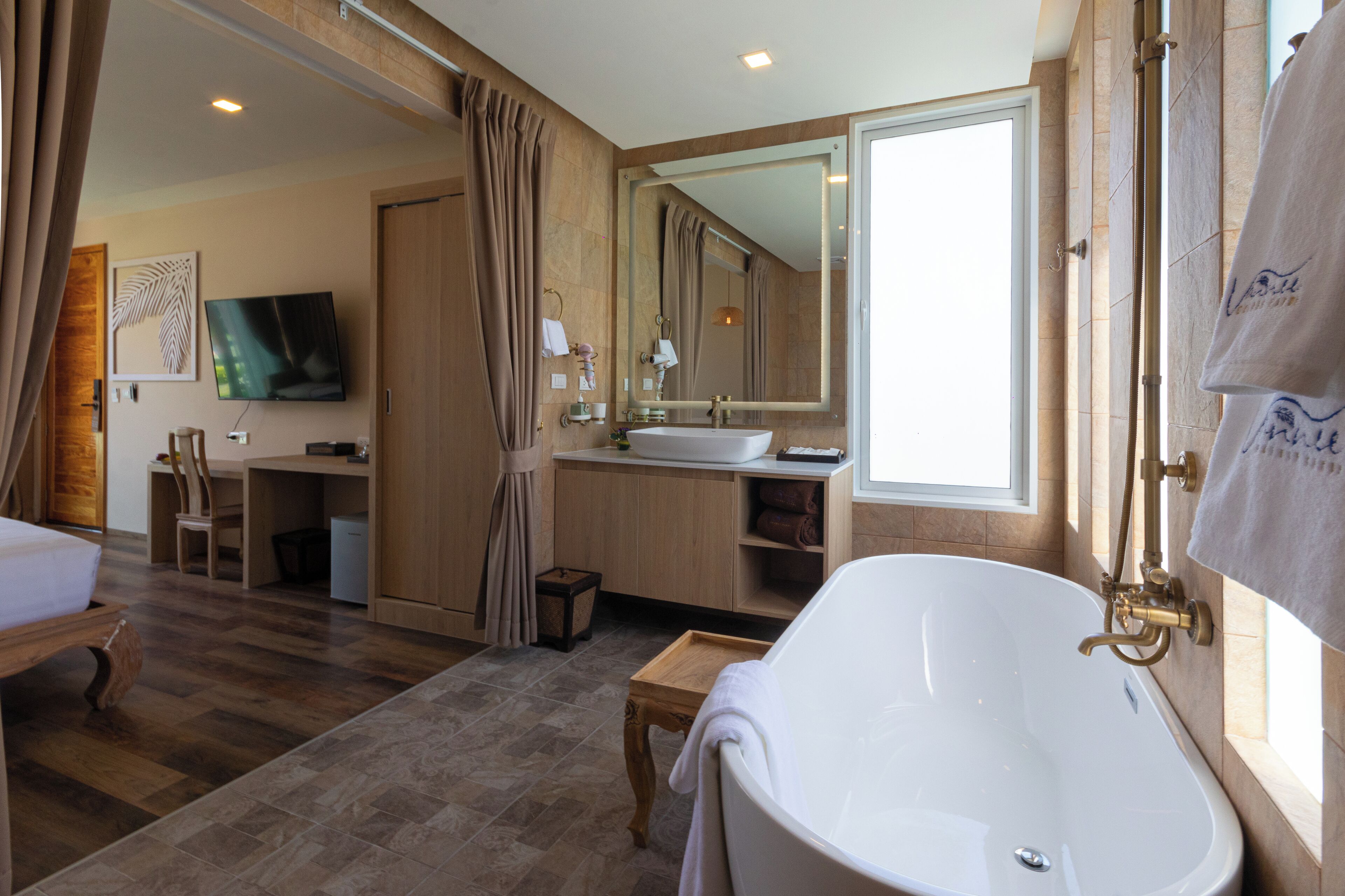 Un baño moderno con una bañera independiente, un espejo grande y un tocador con lavabo.