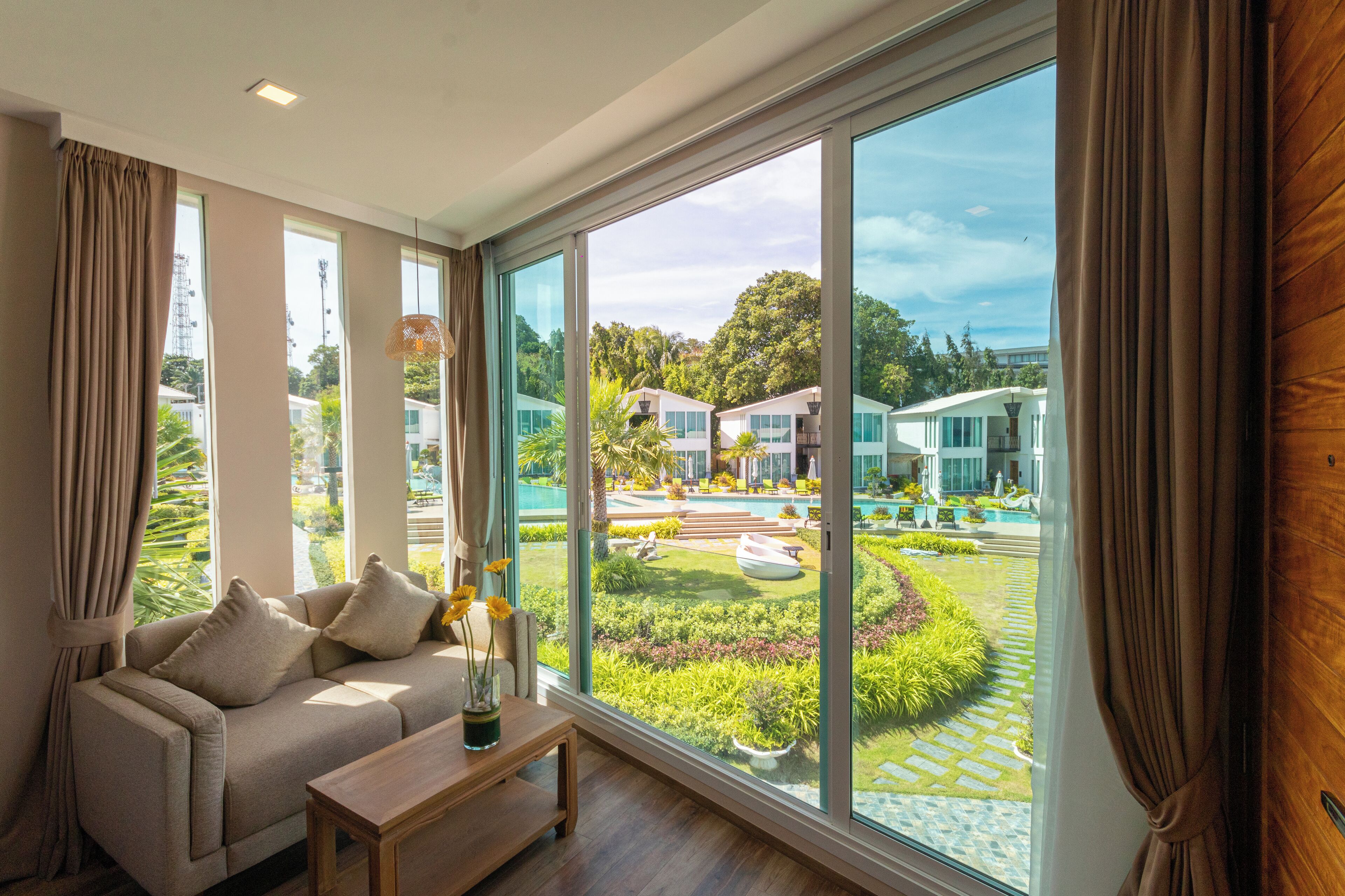 A spacious living room with a large window overlooking a well-maintained garden and pool area.