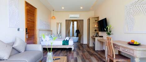 Een moderne hotelkamer met een bank, een houten tafel met een vaas, een bed met uitzicht, een bureau met een stoel en een televisie aan de muur.