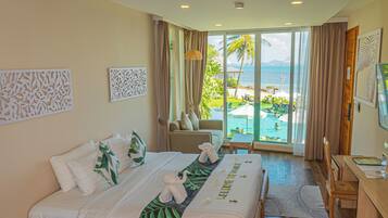 Habitación de hotel con cama, escritorio, silla y vista a una piscina y palmeras.