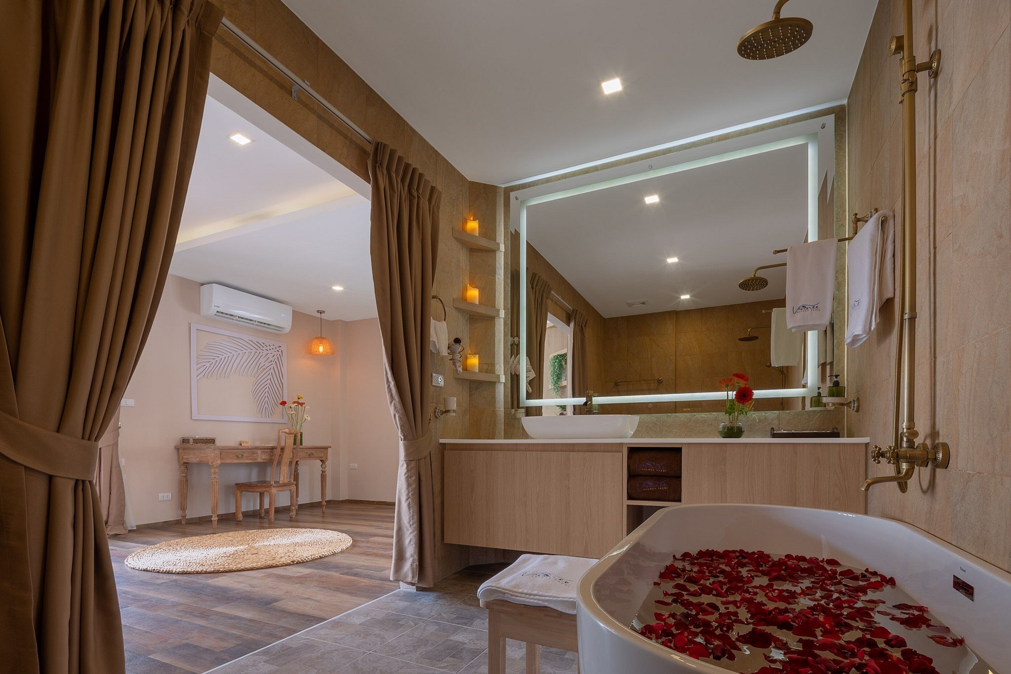 Un baño moderno con una bañera llena de pétalos de rosa, un espejo grande y un cabezal de ducha.