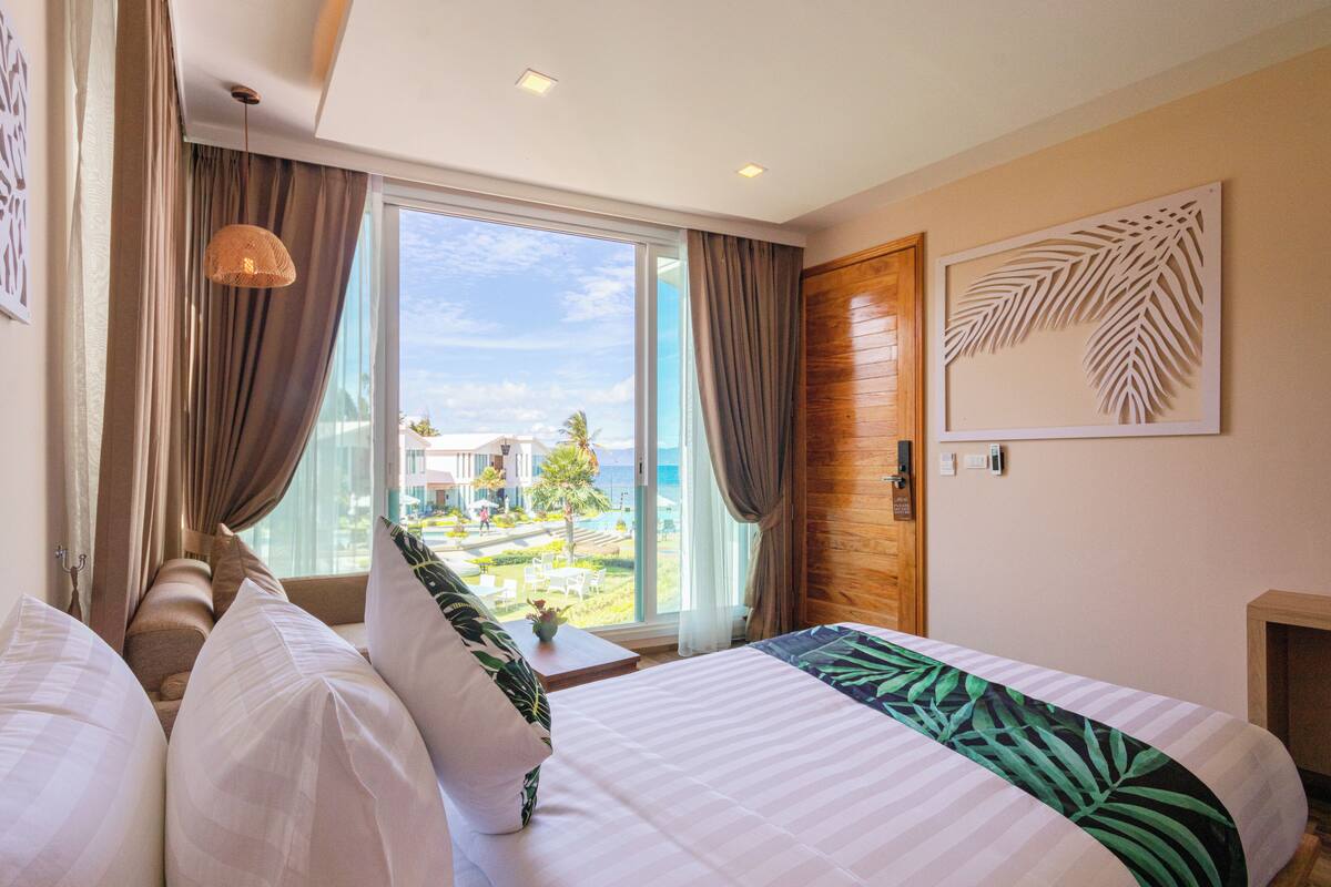 A hotel room with a large bed, a sofa, and a view of the ocean.