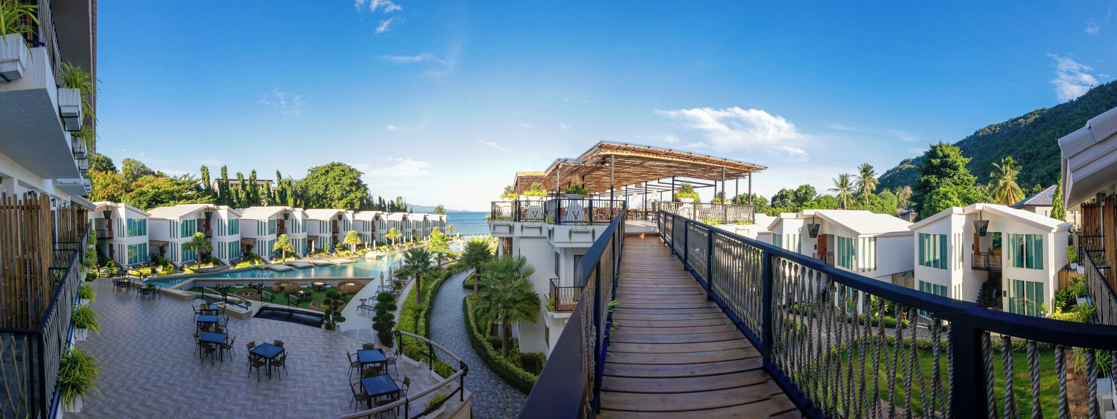 A resort with a pool, outdoor seating, and a view of the sea.