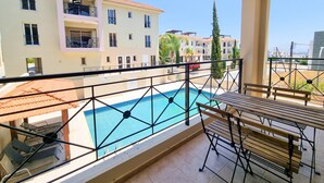 Ein Balkon mit Pool, Gartenmöbeln und Blick auf mehrstöckige Gebäude.