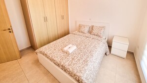 Ein Schlafzimmer mit Bett, Kleiderschrank, Nachttisch und Klimaanlage.