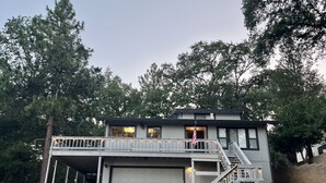 Ein zweistöckiges Haus mit einer Veranda, einer Garage und einer Treppe, die zu einem Balkon führt.