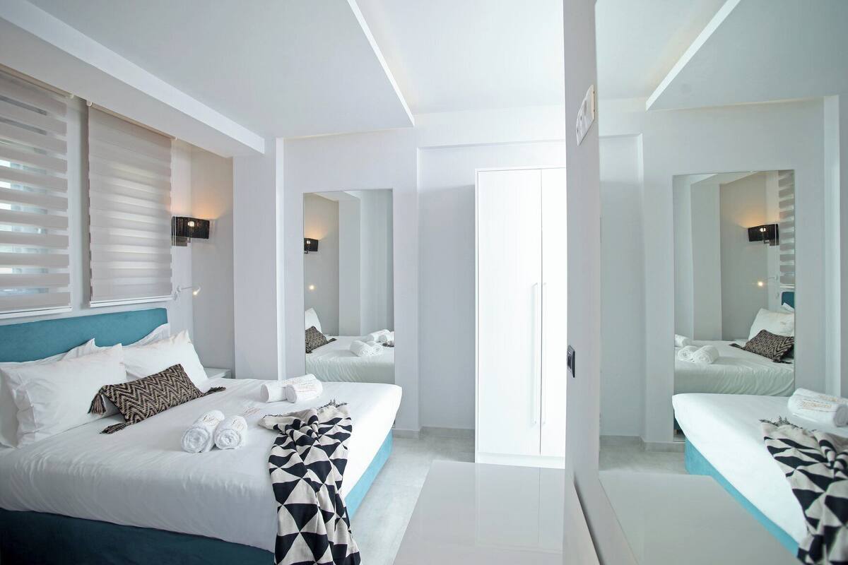 A modern hotel room with a large bed, a mirror, and a view of the hallway.