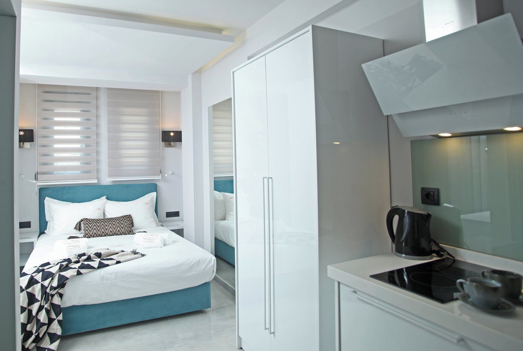 Una habitación de hotel moderna con cama, kitchenette y un espejo grande.