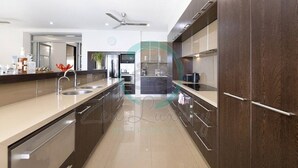 Una cocina moderna con armarios de madera oscura, una isla grande con pileta y un ventilador de techo.
