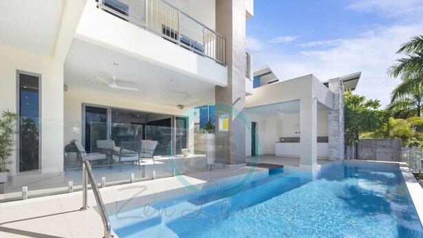 Una casa moderna con piscina, un balcón y una puerta de cristal que da a un patio.