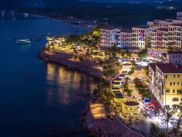 A coastal town with a marina, waterfront restaurants, and multi-story buildings with balconies.