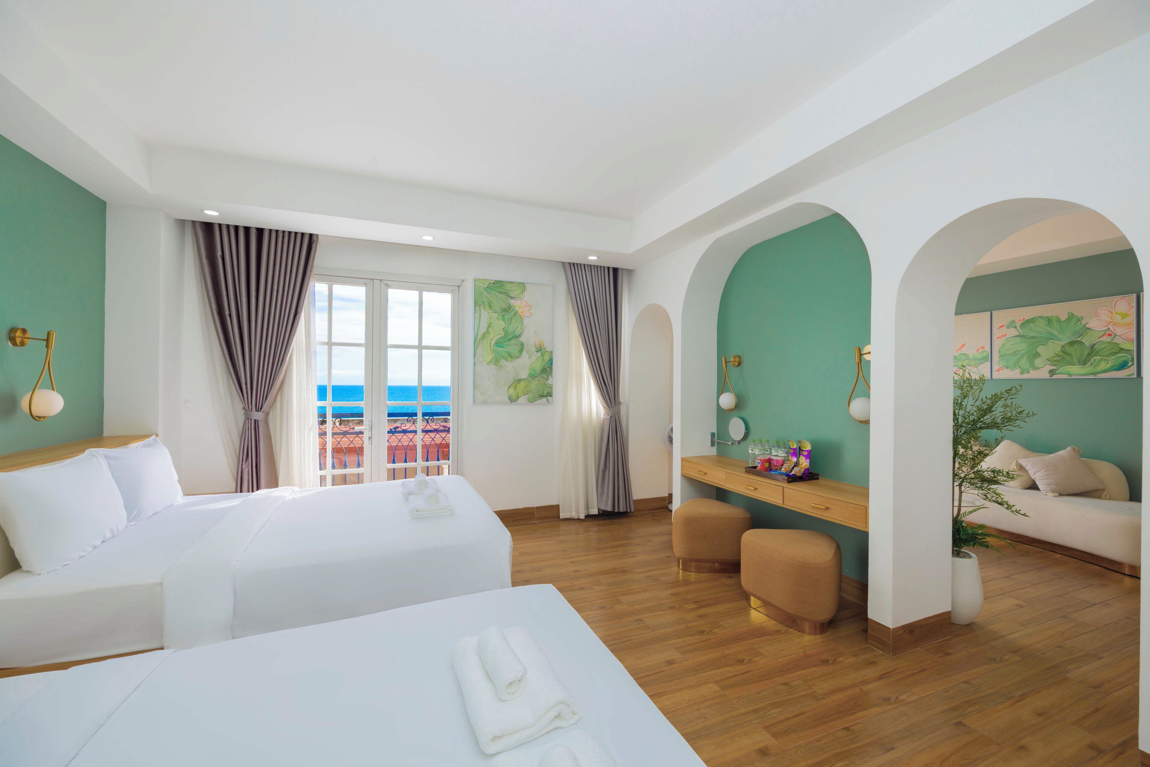 Habitación de hotel con cama, escritorio, zona de estar y vista al mar.