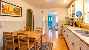 Une cuisine avec des meubles de rangement en bois, un évier et un coin repas comprenant une table et des chaises.