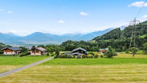 Paisaje rural con casas, una carretera y montañas al fondo.