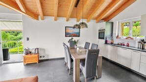 Una cocina moderna con techo de madera, comedor con mesa y sillas, y vistas a zonas verdes.