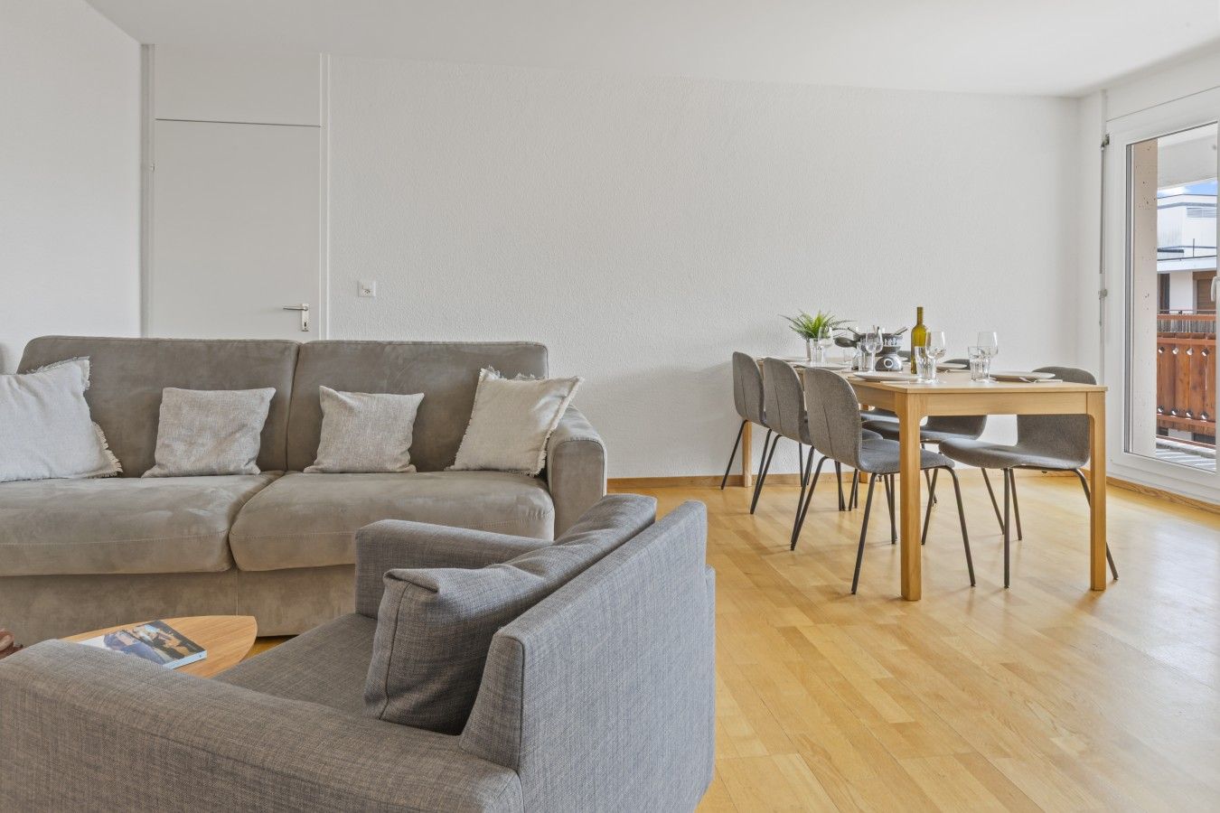 Ein Wohnzimmer mit einer Couch, einem Esstisch mit Stühlen und Holzboden.