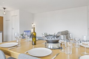 A dining table set with plates, glasses, cutlery, a bottle, and a decorative bowl. - Appartement central et confortable (Crans (VS))