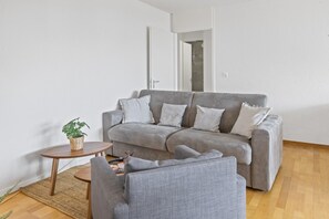 A grey sofa with pillows, a small round table with a plant, and a grey armchair. - Appartement central et confortable (Crans (VS))