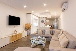 A modern living room with a sofa, a glass coffee table, and a TV mounted on the wall. - Modern Beautiful Pool And Sea Apt Qawra (St. Paul's Bay)