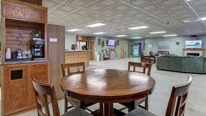 A spacious room with a wooden reception desk, a round table with chairs, and a green sofa.