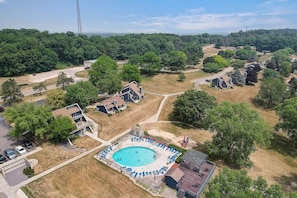 Vue aérienne d’un quartier résidentiel avec une piscine entourée de chaises longues et d’une terrasse.
