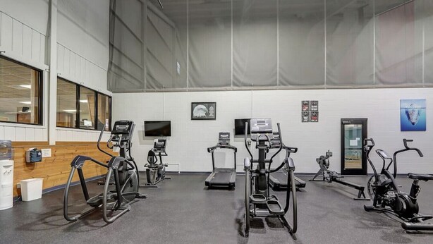 A gym with various exercise equipment, including treadmills and stationary bikes, arranged in rows.