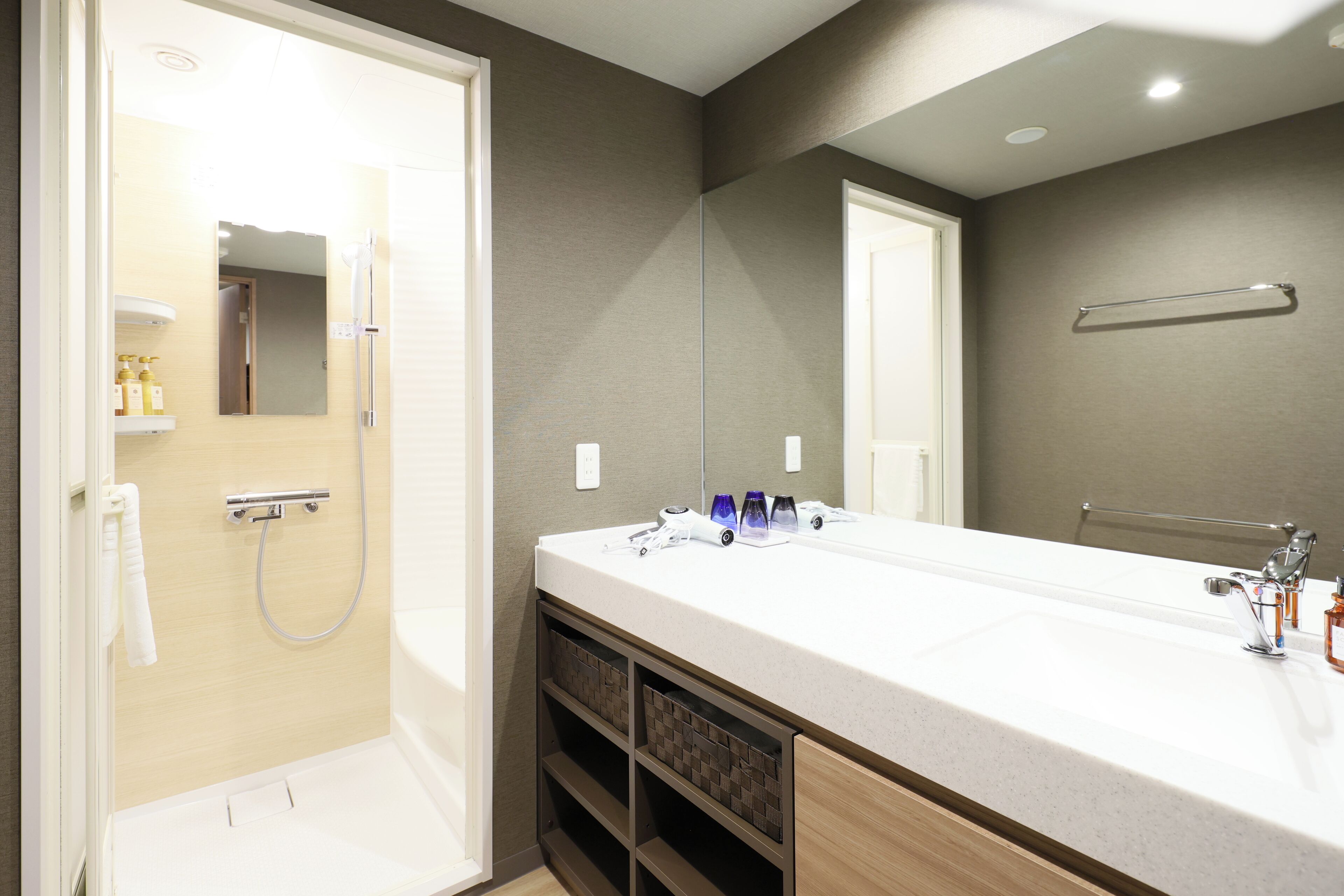 A modern bathroom with a double sink, a shower, and a large mirror.