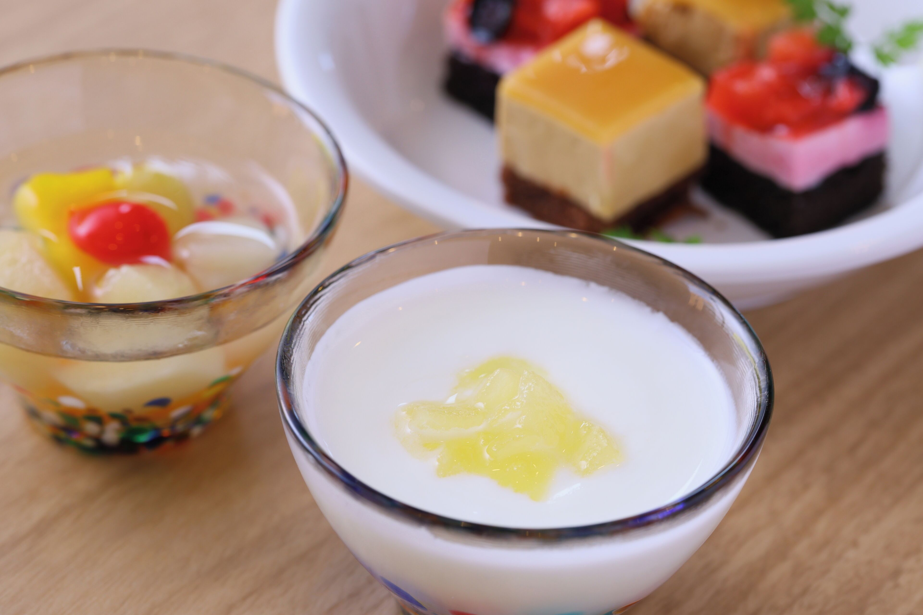 A dessert setting with two glasses of a creamy dessert and a plate of assorted desserts.
