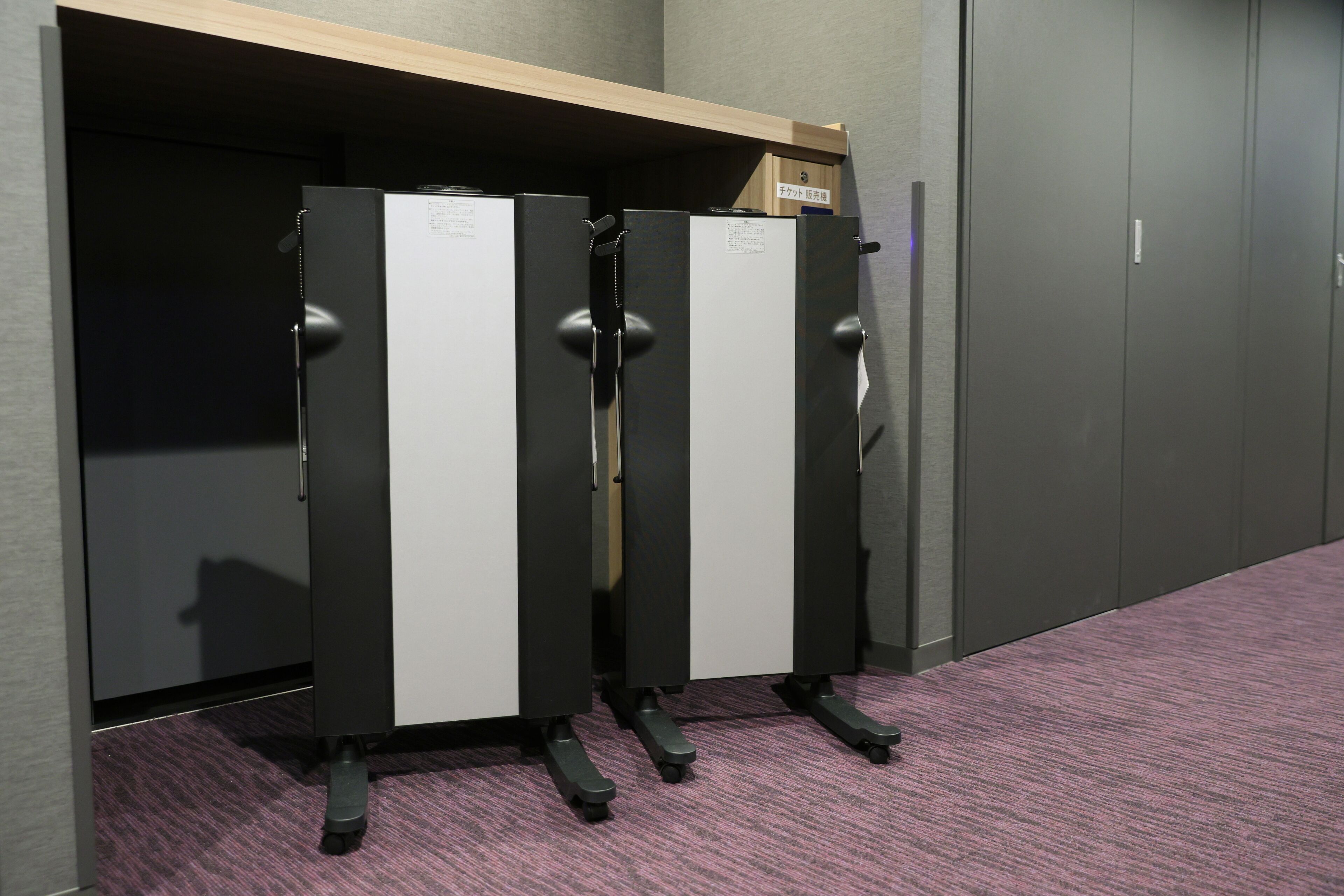 A row of black and white lockers with a wooden shelf above them.