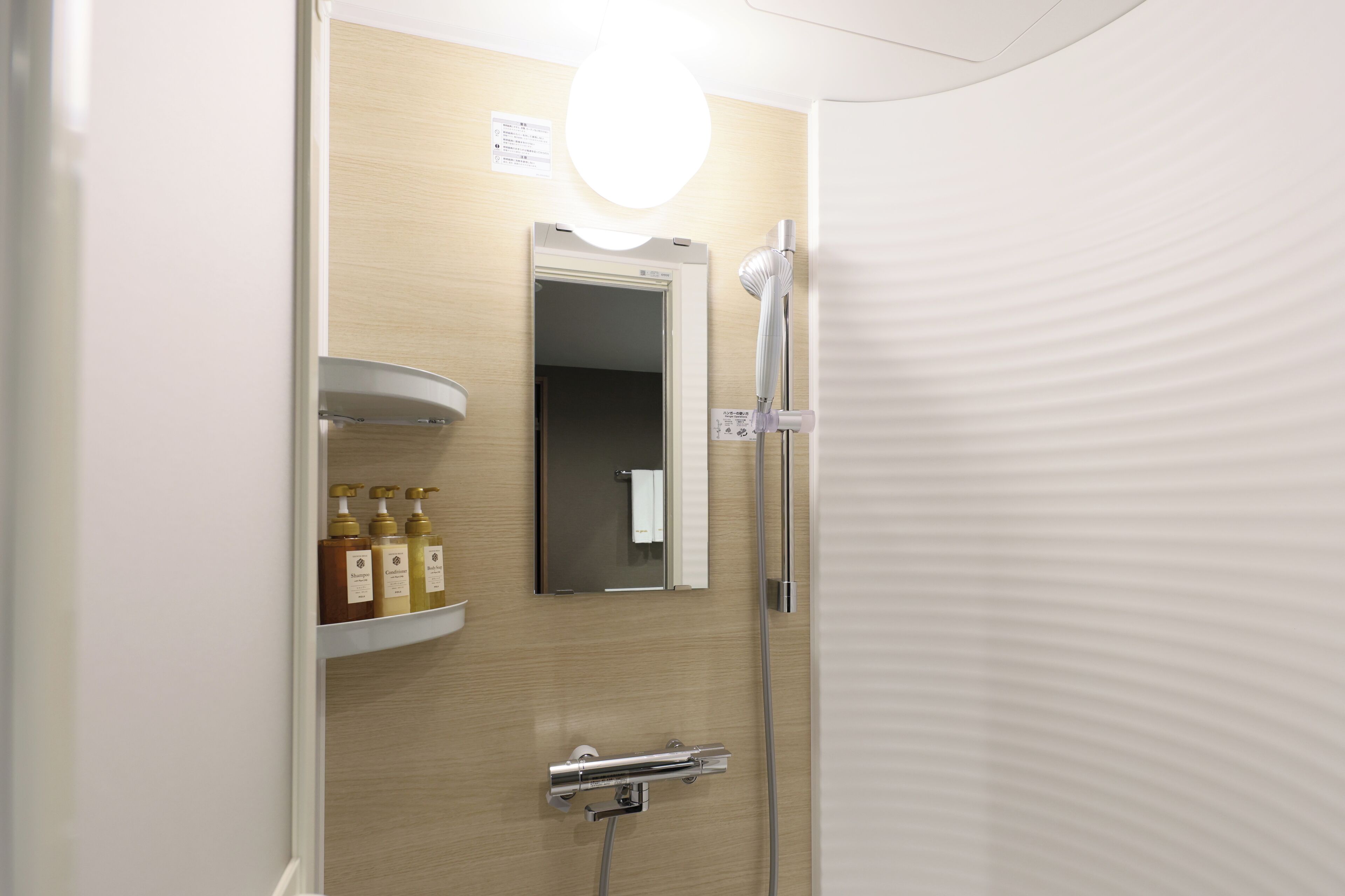 A bathroom with a wooden vanity, a mirror, and a shower.