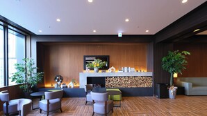 Eine moderne Lobby mit Kamin, Sitzgruppe und großen Fenstern.