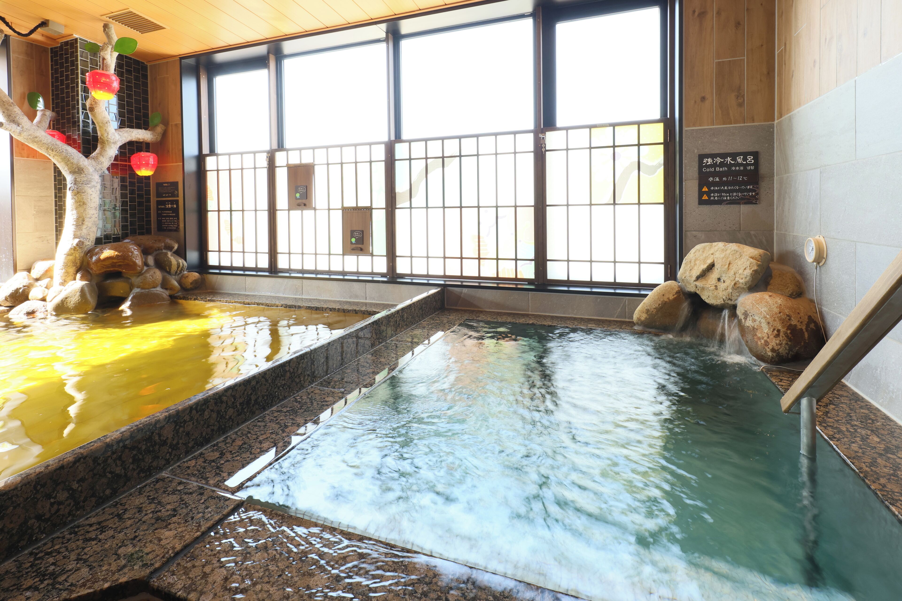 A hot spring area with a tree decoration, a stone wall, and a wooden floor.