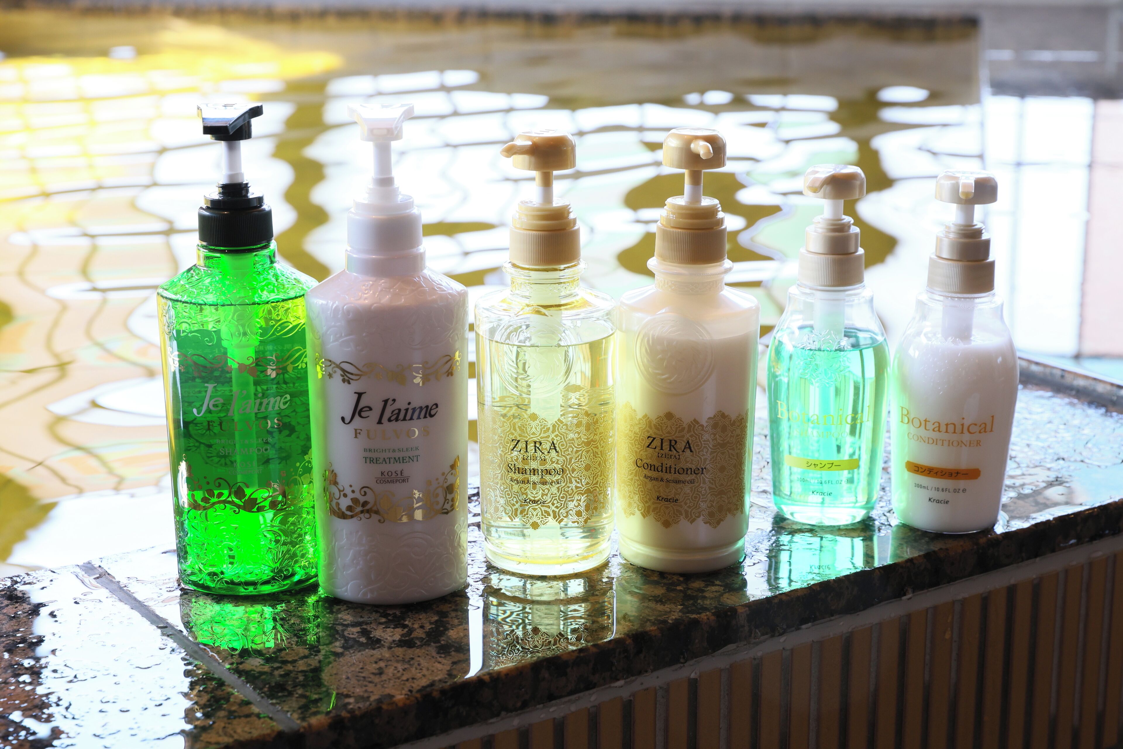 A row of toiletries on a wet surface, likely a bathroom counter.