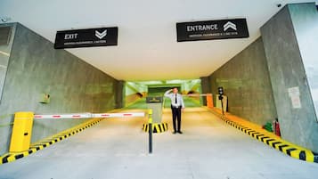 An indoor passageway with exit and entrance signs, a security guard, and a yellow safety barrier.
