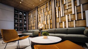 A modern interior with a grey sofa, a round white table, and a brown chair. - Bayprime Hotel  (Parañaque)