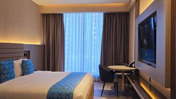 A modern hotel room with a large bed, a desk, and a television.