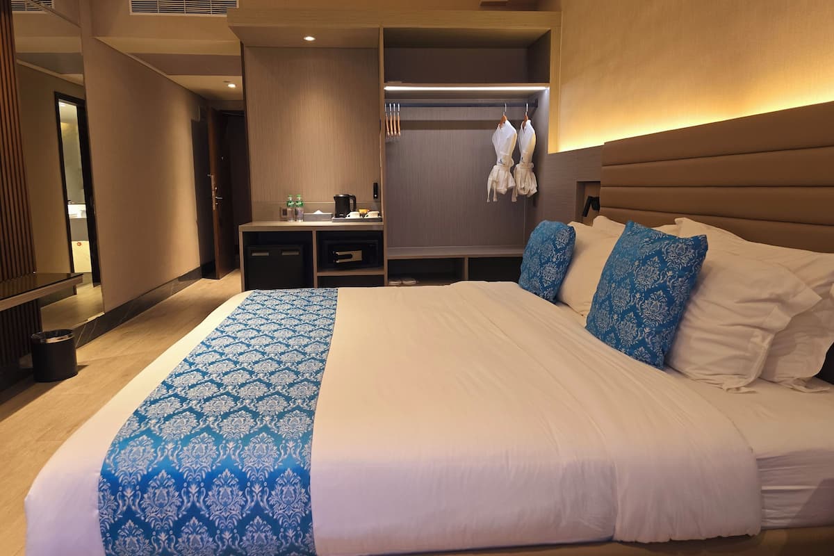 A hotel room with a large bed, a bedside table, a wardrobe, and a mirror.