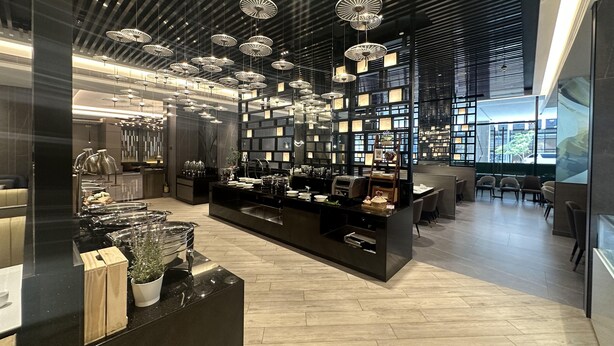A modern interior with a central display area, hanging pendant lights, and a seating area with chairs. - Bayprime Hotel  (Parañaque)