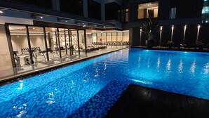 A swimming pool with a glass enclosure, exercise equipment, and lounge chairs. - Bayprime Hotel  (Parañaque)