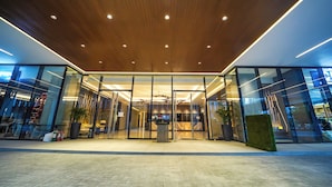 A modern building entrance with glass doors, a wooden ceiling, and a tiled floor. - Bayprime Hotel  (Parañaque)