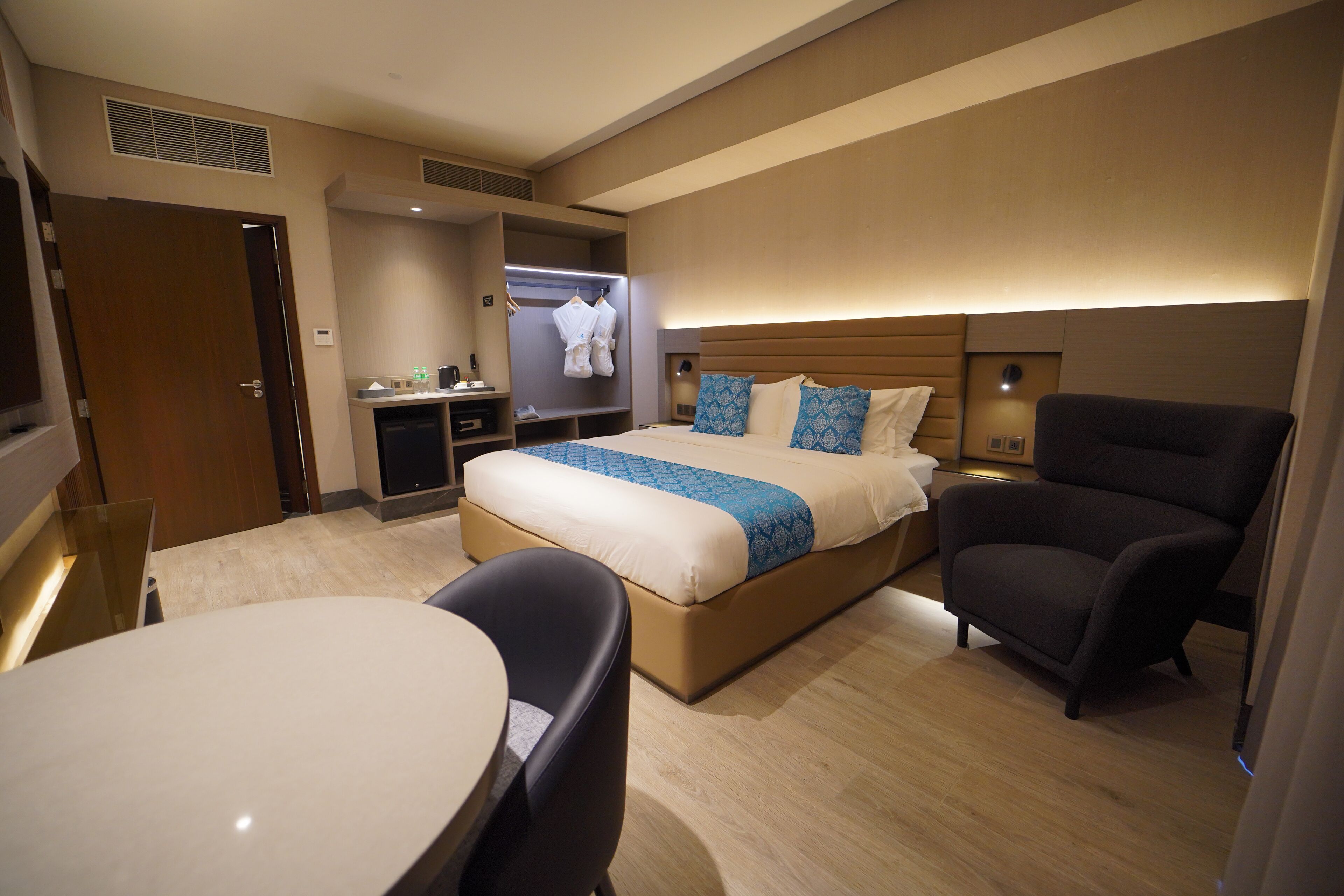 Una habitación de hotel con cama, escritorio, silla, televisor y armario.