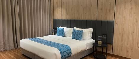 A hotel room with a large bed, a nightstand, a lamp, and a wooden wardrobe.