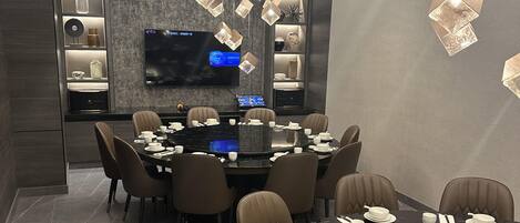 A modern dining area with a large round table set for a meal, surrounded by comfortable chairs.