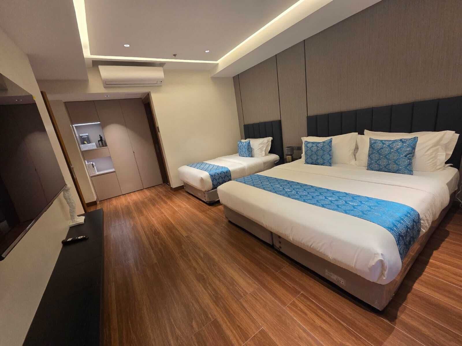 A hotel room with two beds, a flat-screen TV, and a wooden floor.