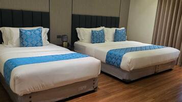 A hotel room with two beds, wooden flooring, and a modern design.